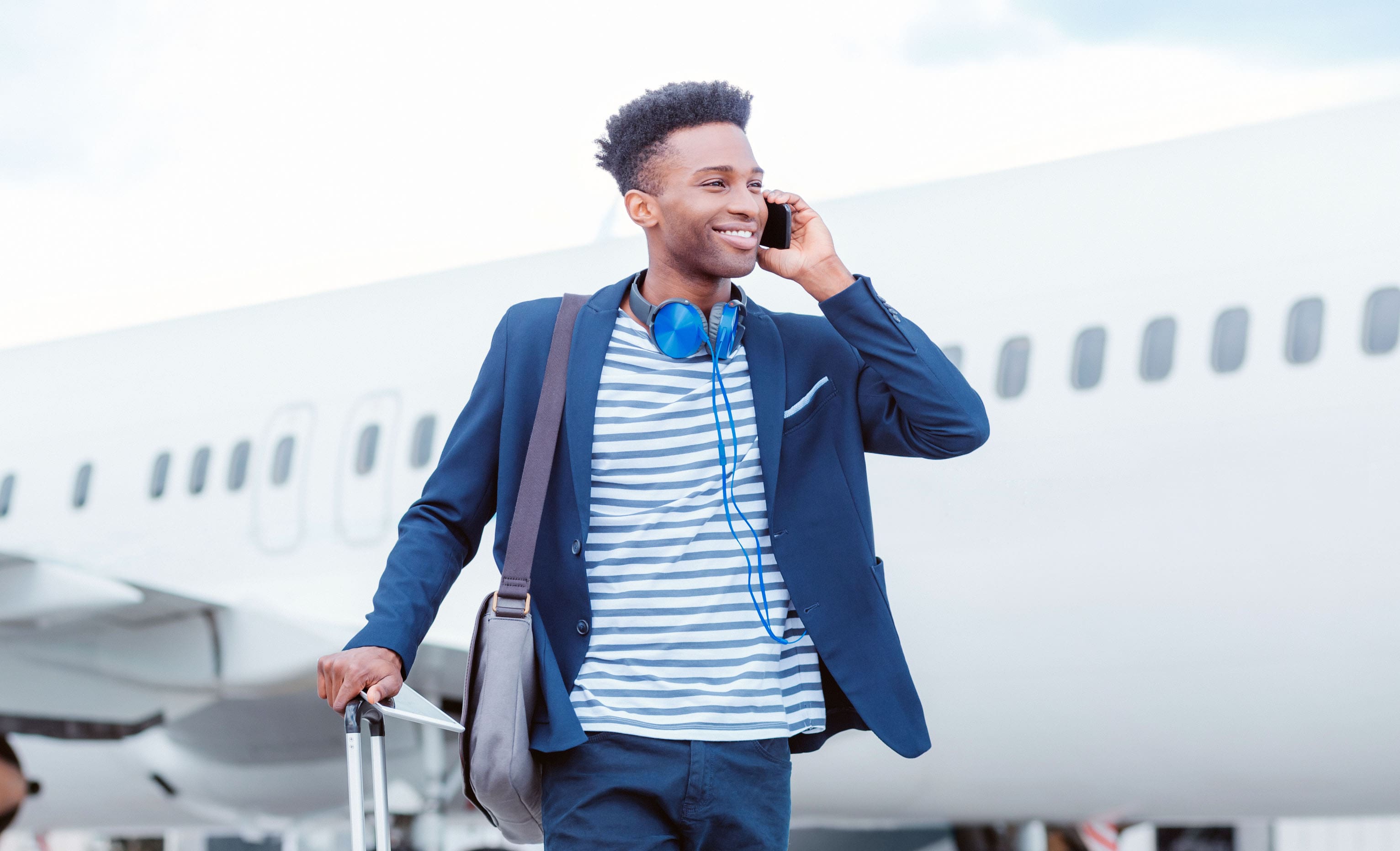 Photo of man standing at airport talking via smartphone