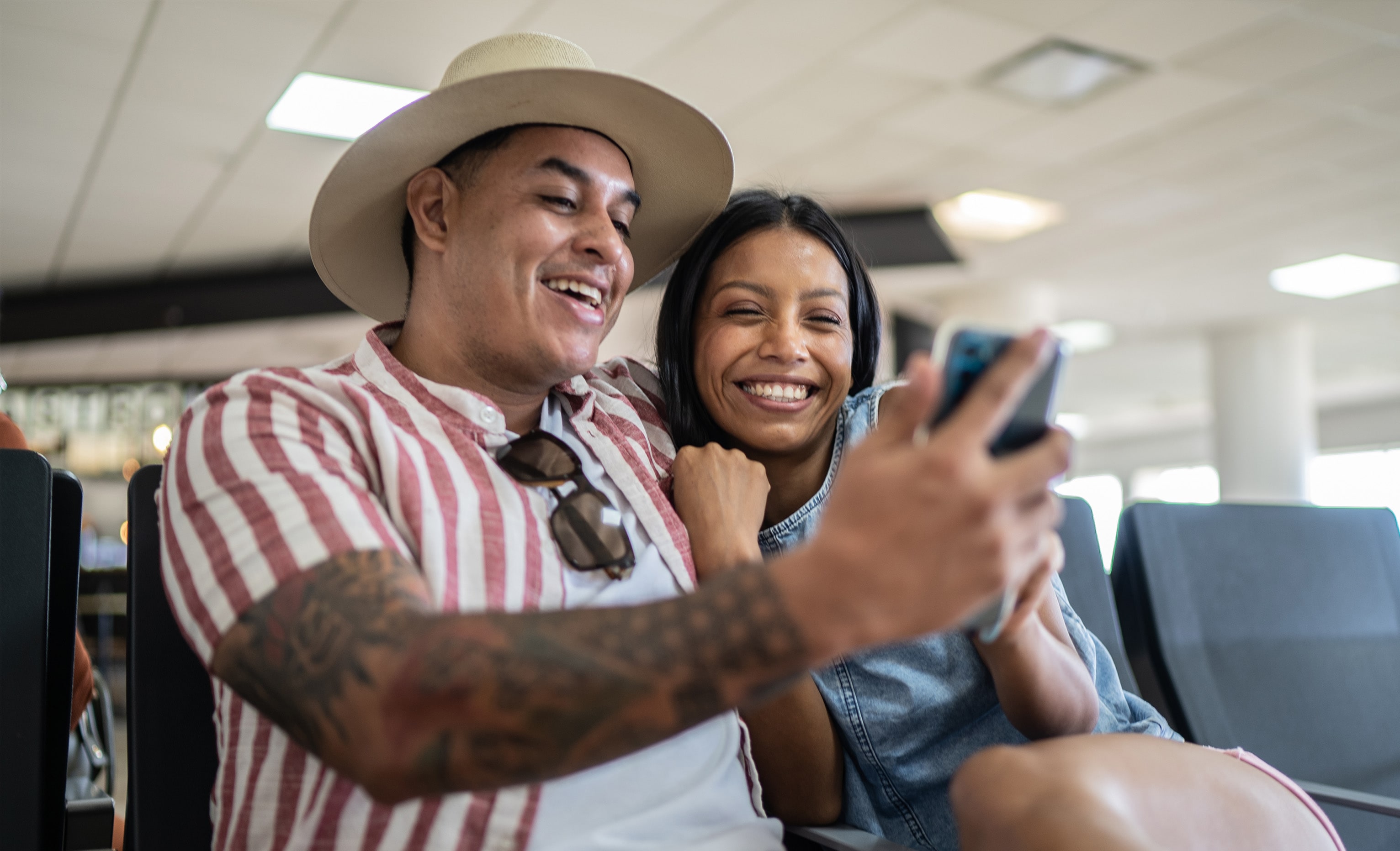 Couple smiling at smartphone in airport