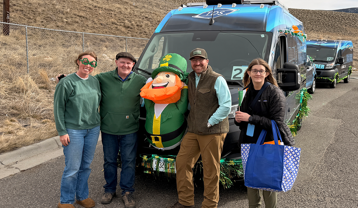 Four people smiling in front of a TDS van