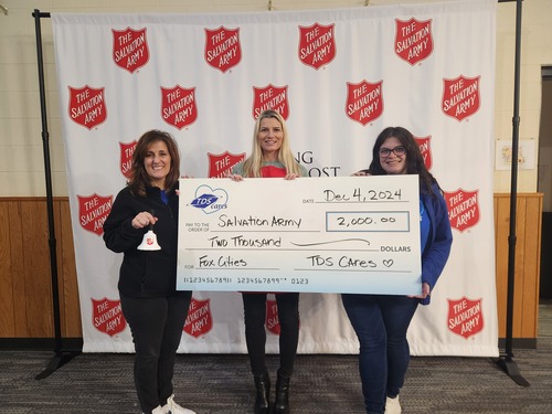 Three people smiling at camera holding a TDS Cares check for Salvation Army