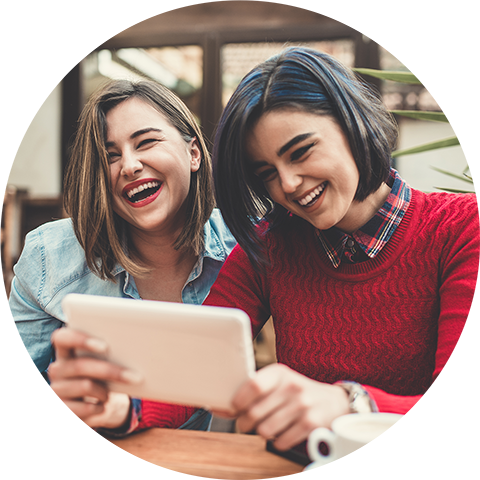 Two women laughing and watching videos on a phone