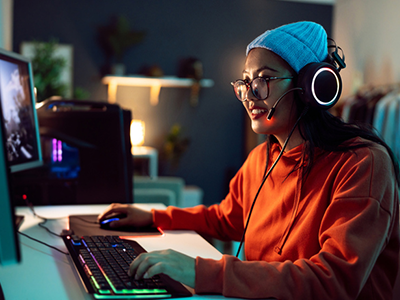 Ping Powered Precisions A woman playing a computer game in a dimly lit home office room